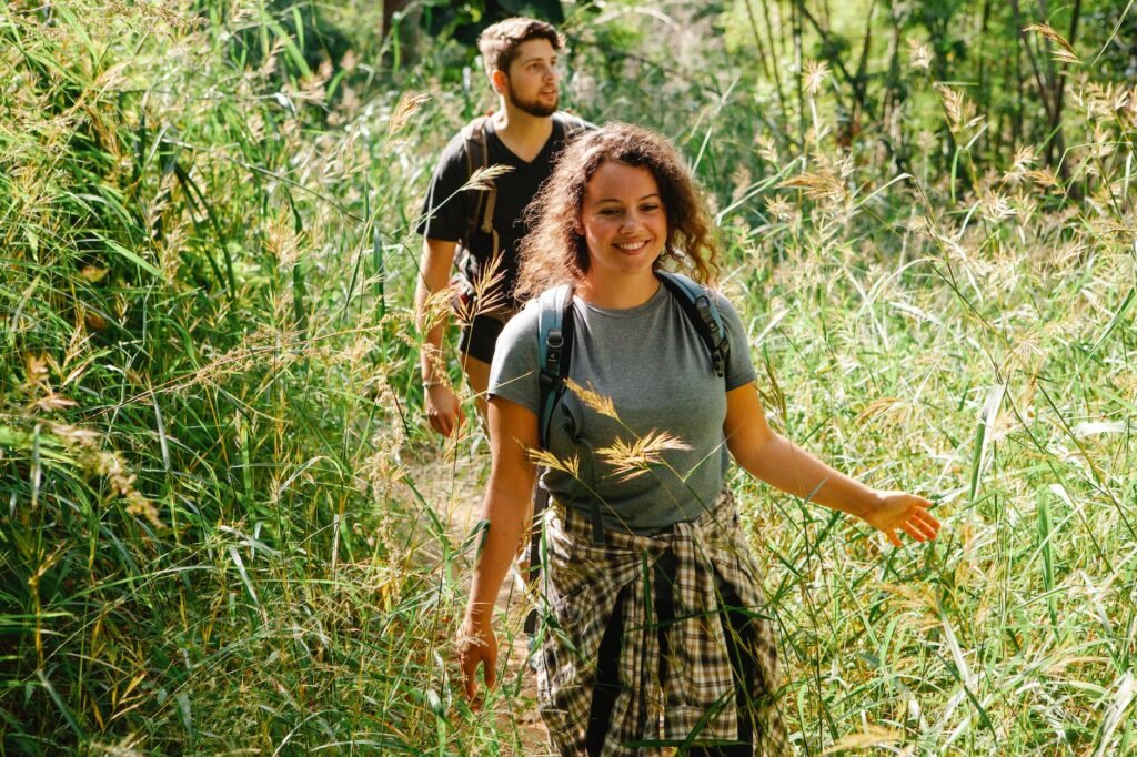 cheerful hikers between lush green grass in sunlight