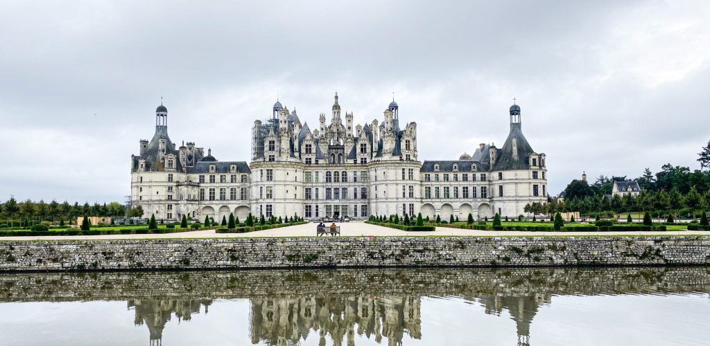 Wide angle view of Castle of Chambord in Loire valley, with its gardens, Cloudy day, water reflection, France Wide angle view of Castle of Chambord in Loire valley, with its gardens, Cloudy day, water reflection, France